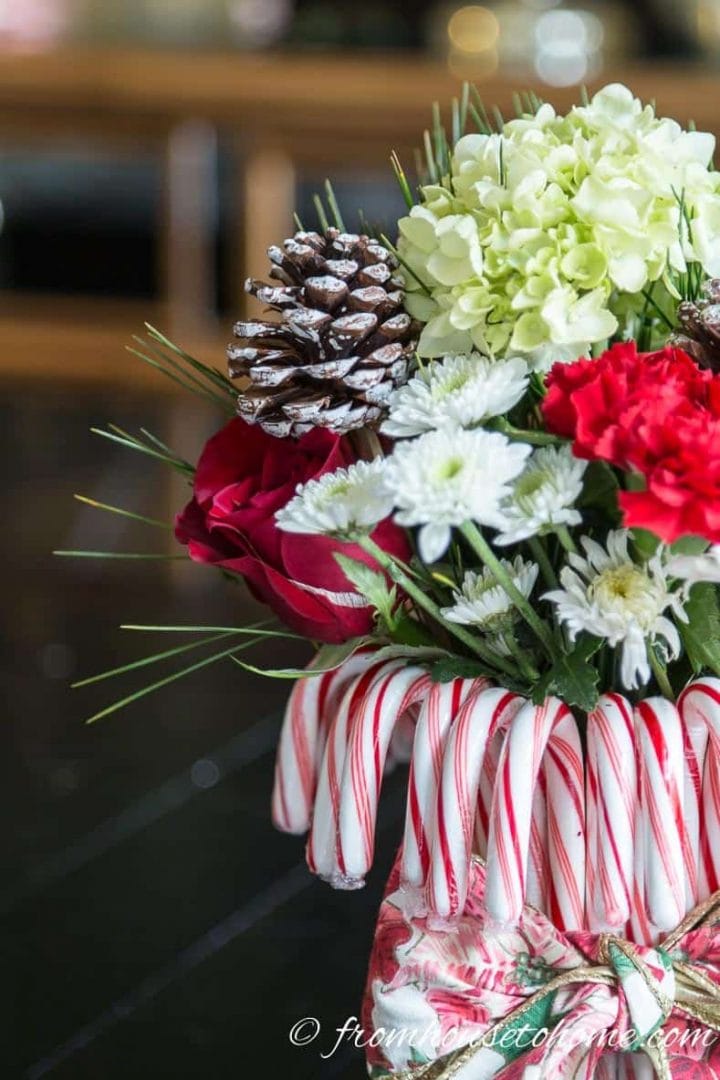 White hydrangea, red roses and red and white mums with pine needles and pine come picks in a DIY candy cane vase