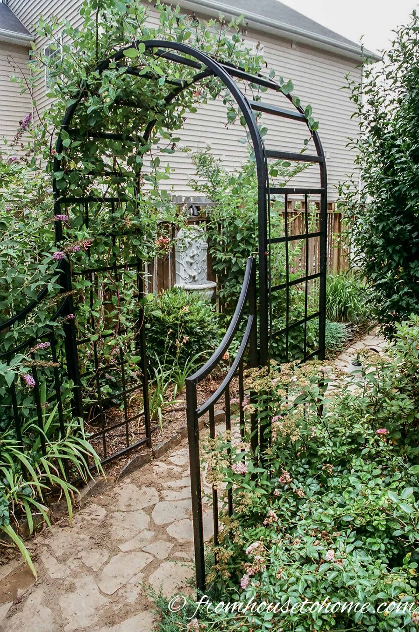 Black arched metal arbor with garden gate