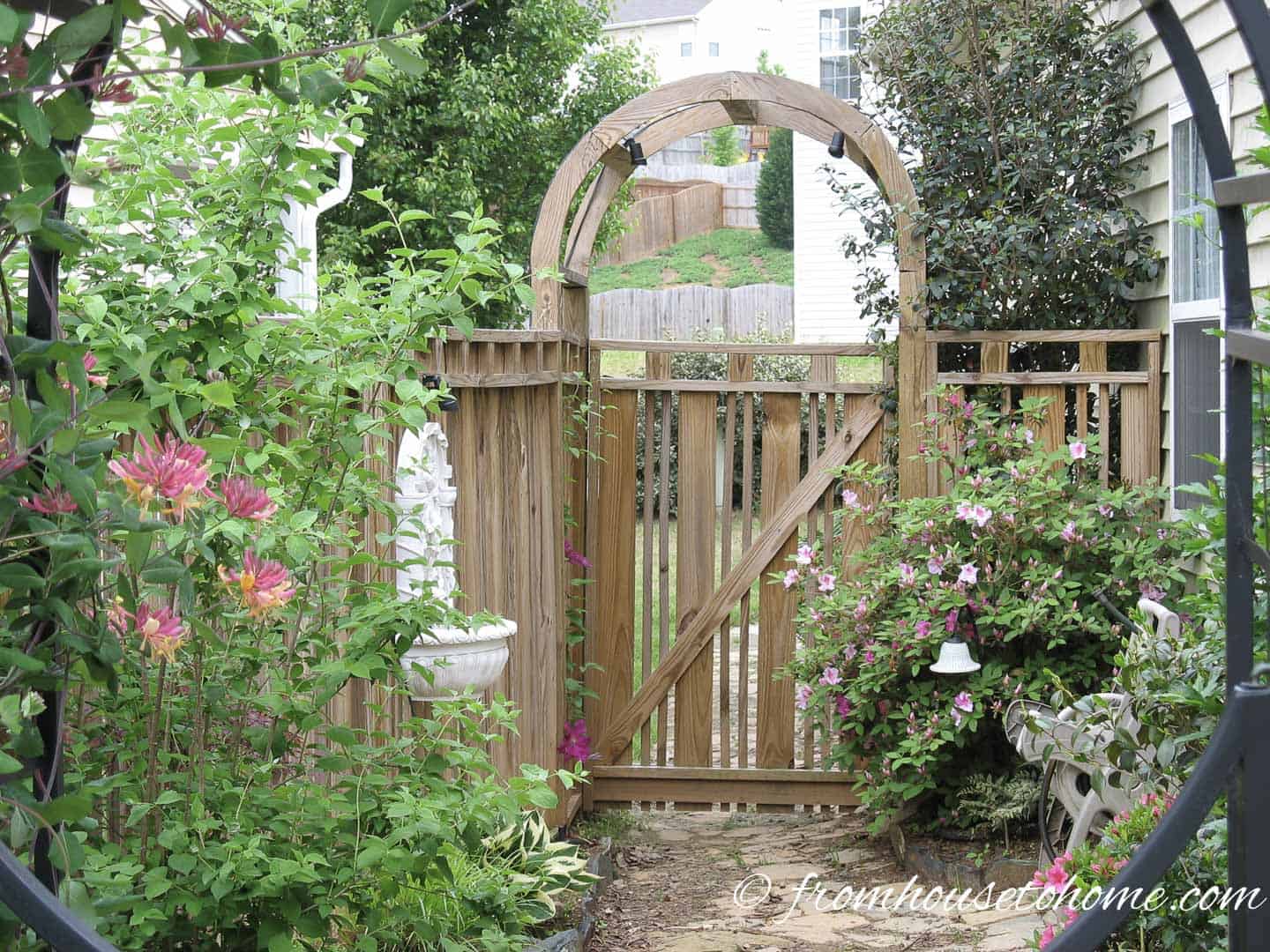 Wood fence gate with an arch arbor at the entrance of the garden
