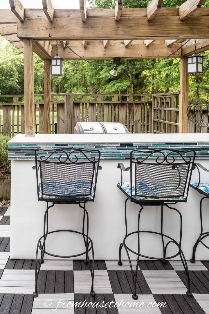Tiled outdoor bar with a white faux leather front and a pergola