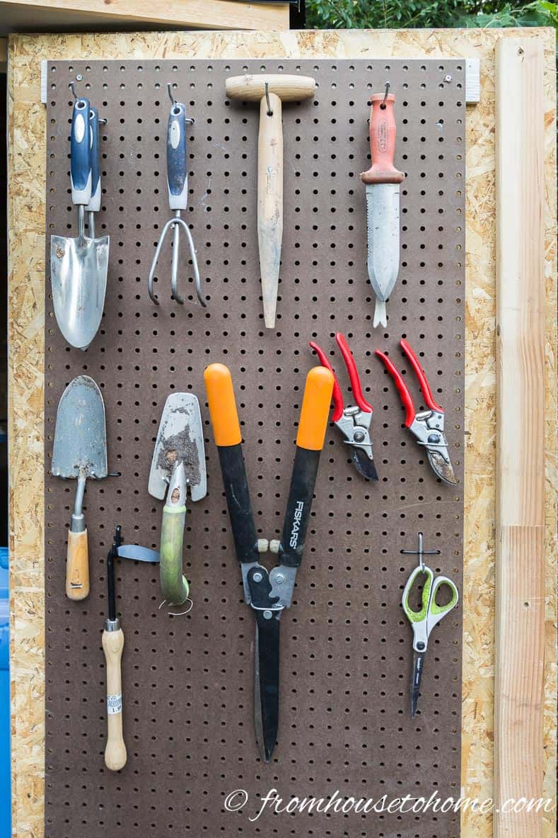Garden tools hanging on a pegboard on a shed door