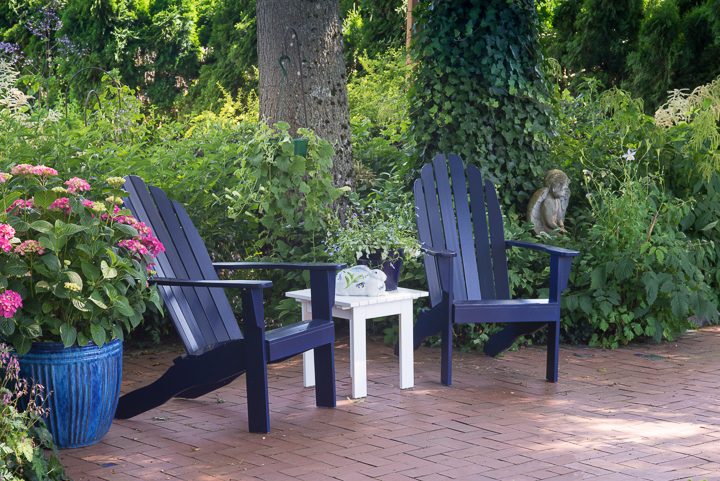 Blue Adirondack chairs with a white table on a patio ©Jamie Hooper - stock.adobe.com