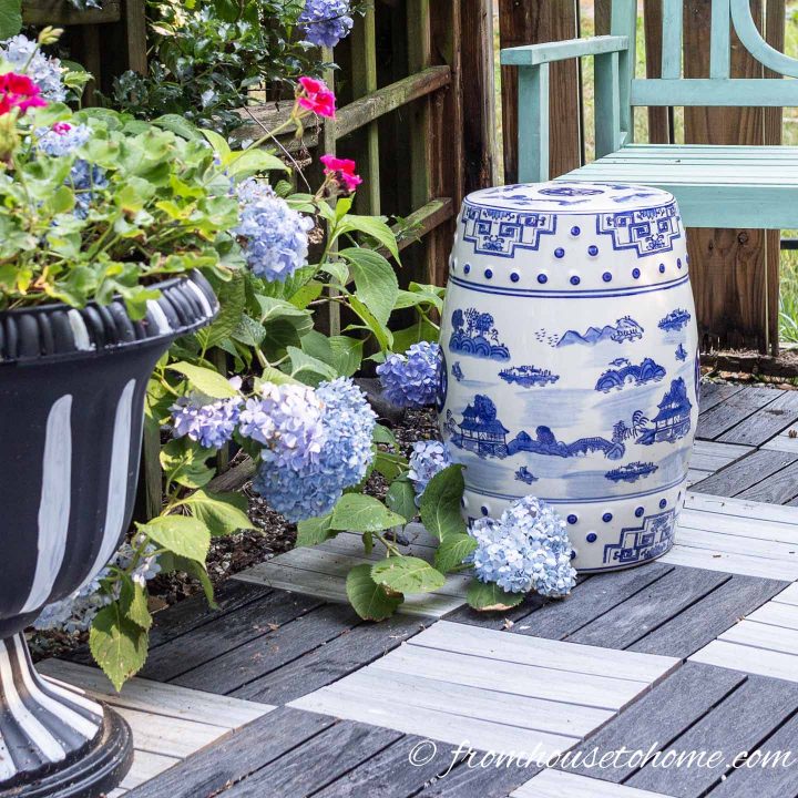 Blue and white garden stool beside blue hydrangeas