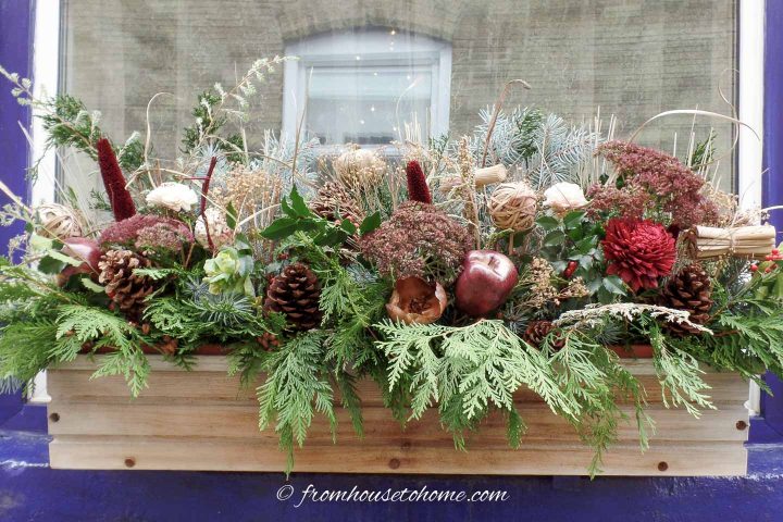 Winter window box with evergreens, pine cones, twigs and faux flowers