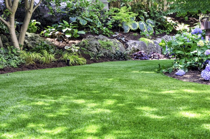 Fake grass in a hillside shade garden design ©Joanne Dale - stock.adobe.com