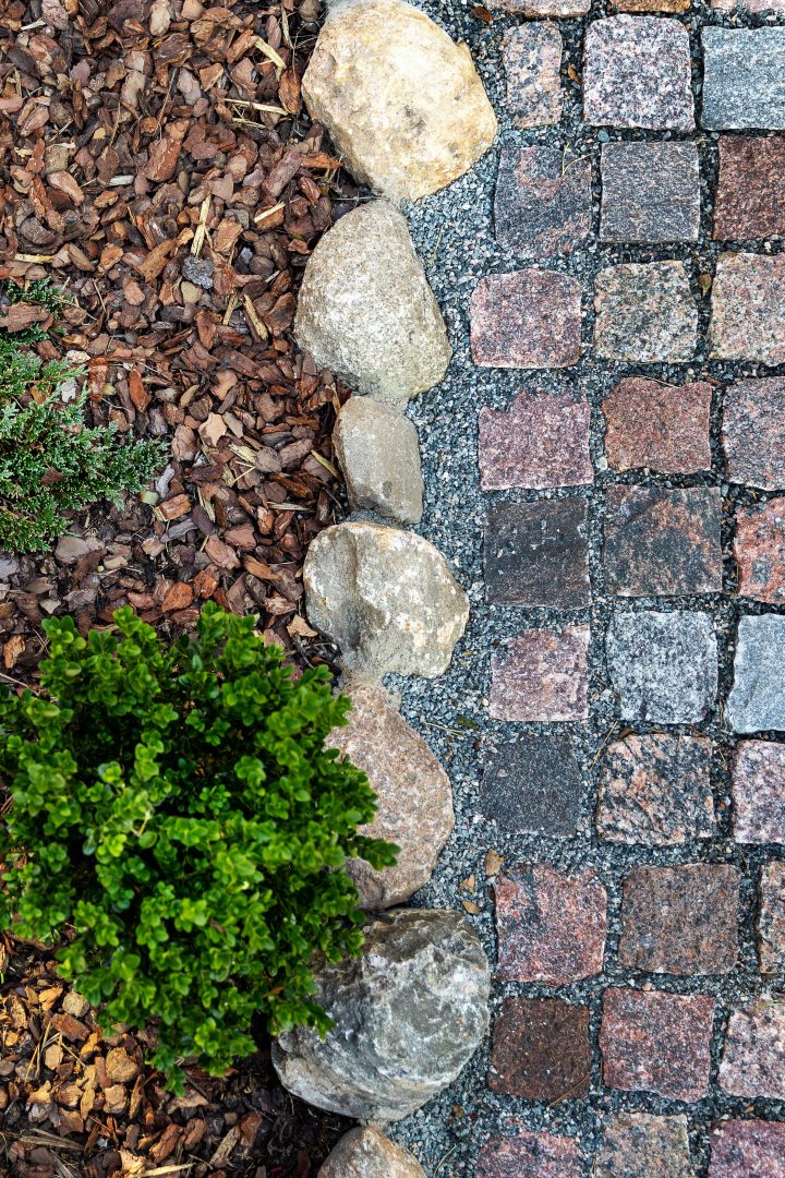 Rocks separating a cobblestone pathway from the garden