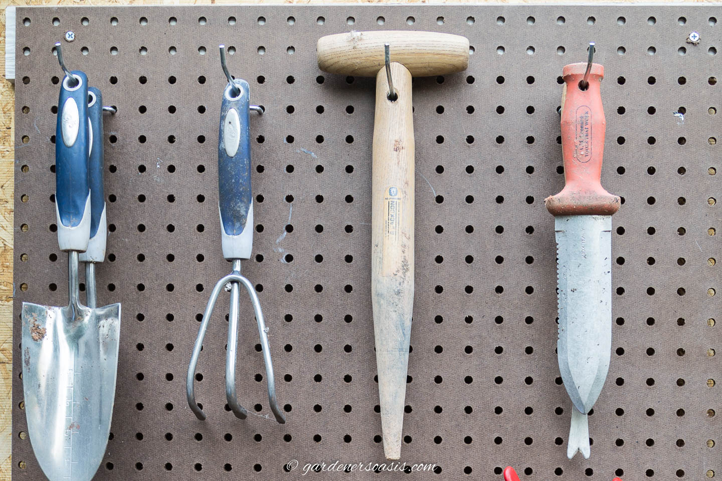 garden hand tools with holes in the handles hung on pegboard with straight hooks