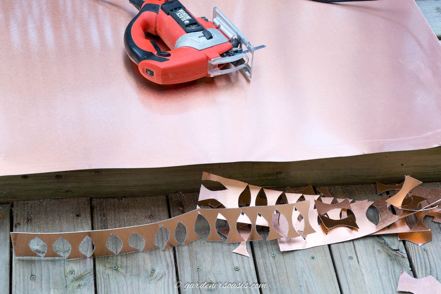 Jig saw on top of a copper metal sheet with the end cut off of it