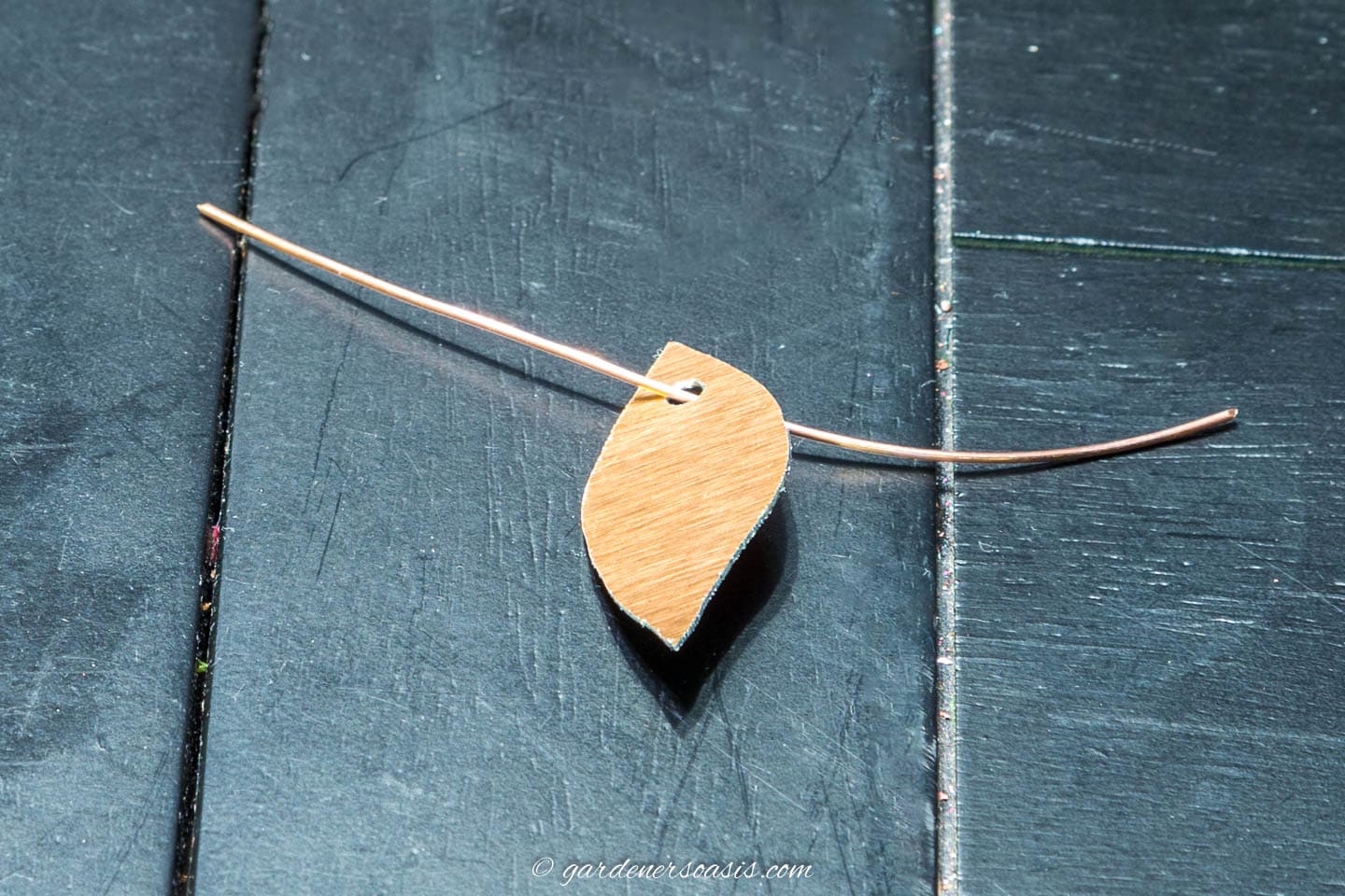 A copper leaf with a small copper wire threaded through a hole at the top