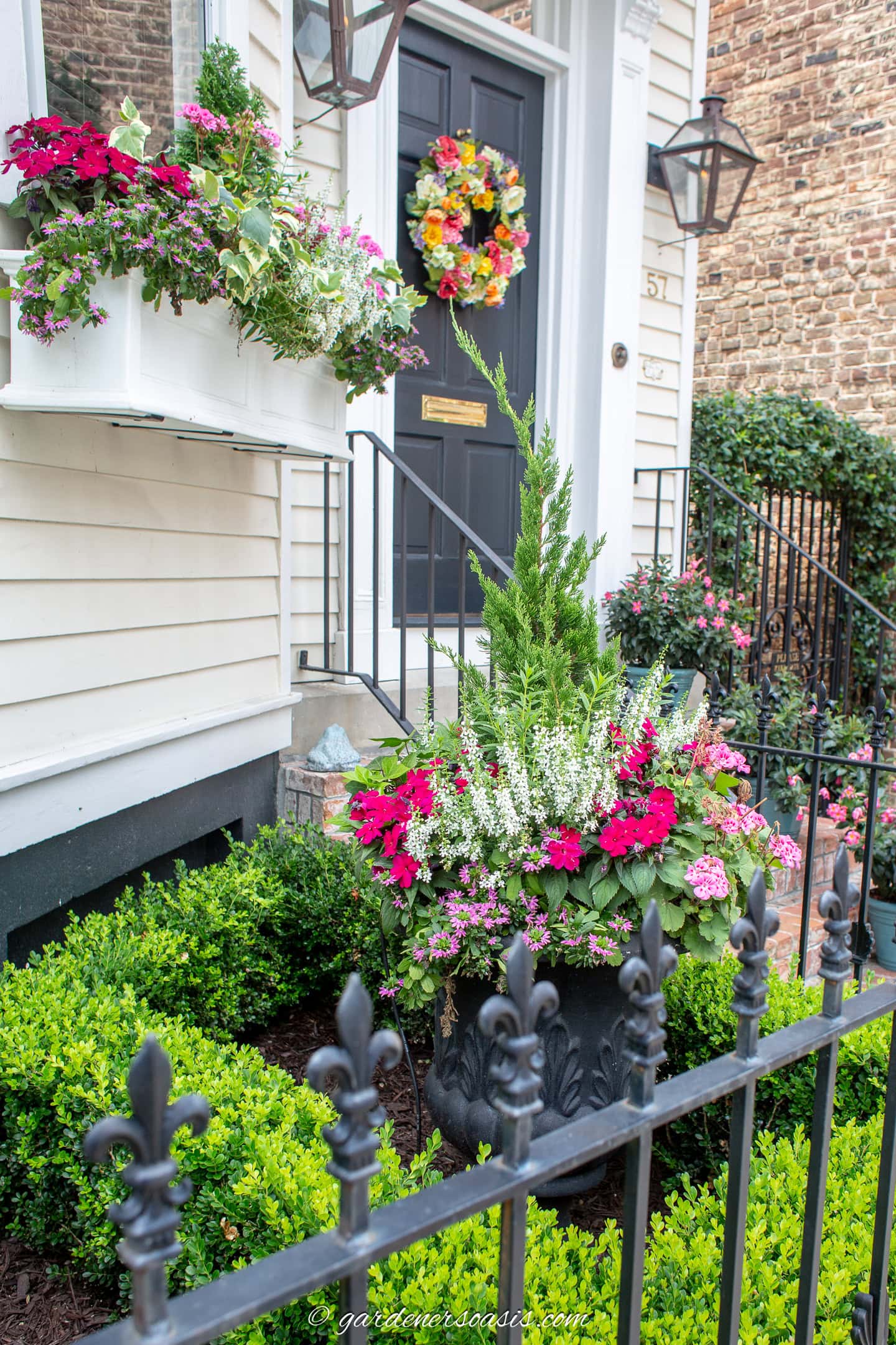 An urn in the garden planted with the same plants as the window box above it