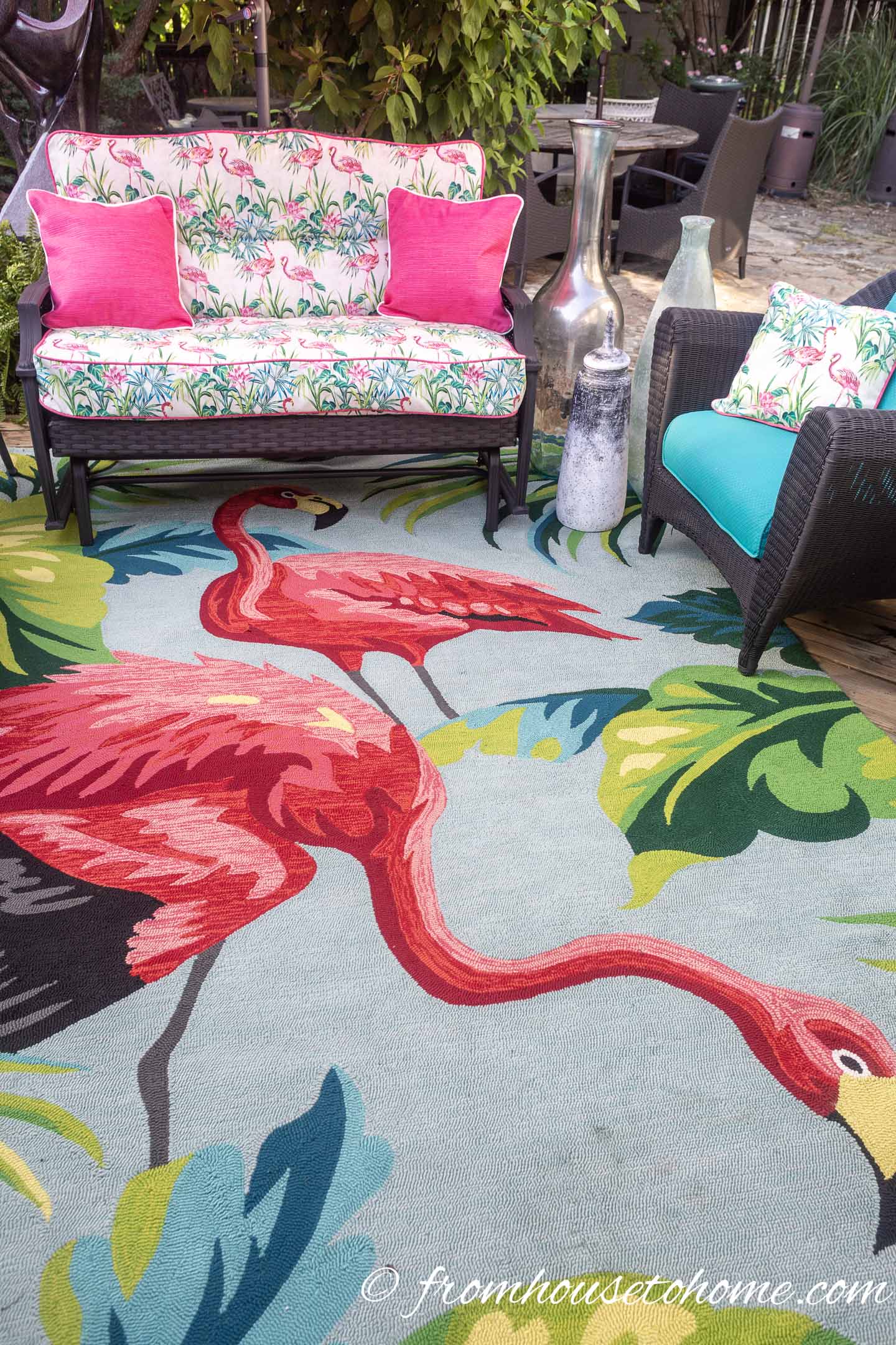 An outdoor sofa and lounge chair on a pink and turquoise rug with a flamingo pattern