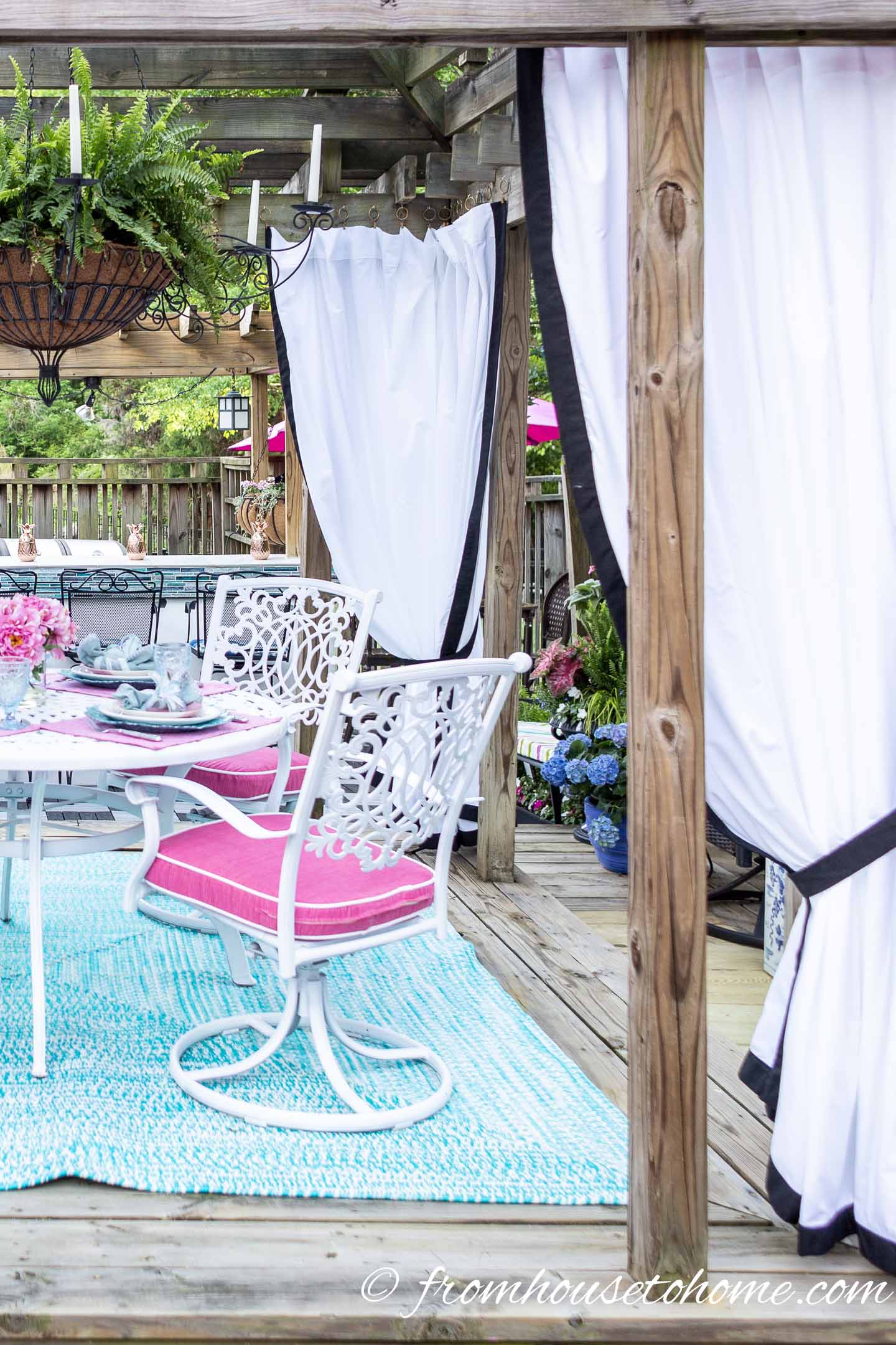 White outdoor curtains hung on a gazebo around a small deck