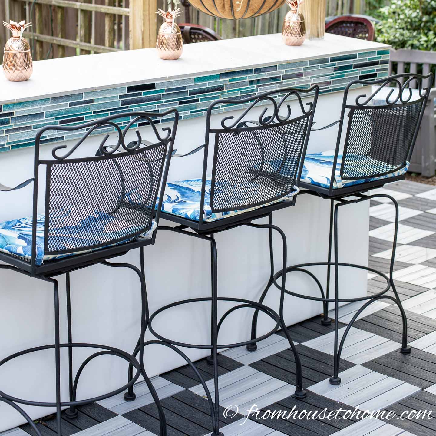 Bar stools pulled up to a white and turquoise outdoor bar