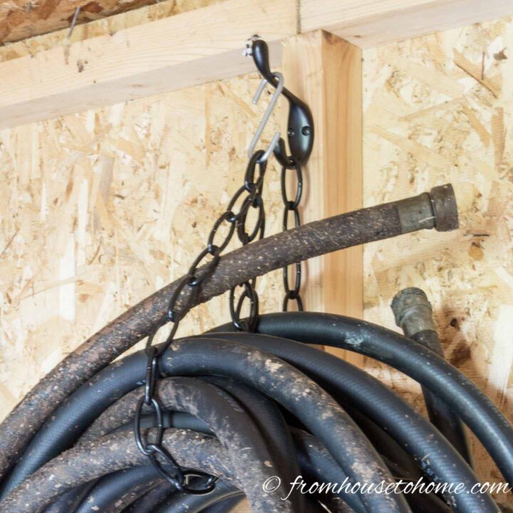 hose hung by a chain and hook in a shed