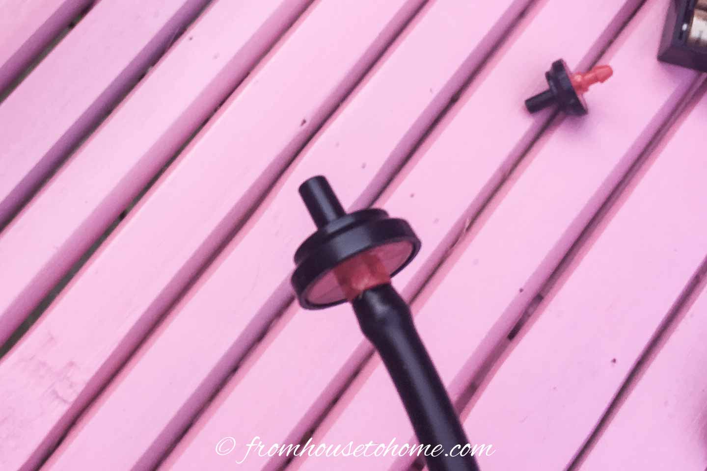 An emitter installed at the end of a container watering system hose