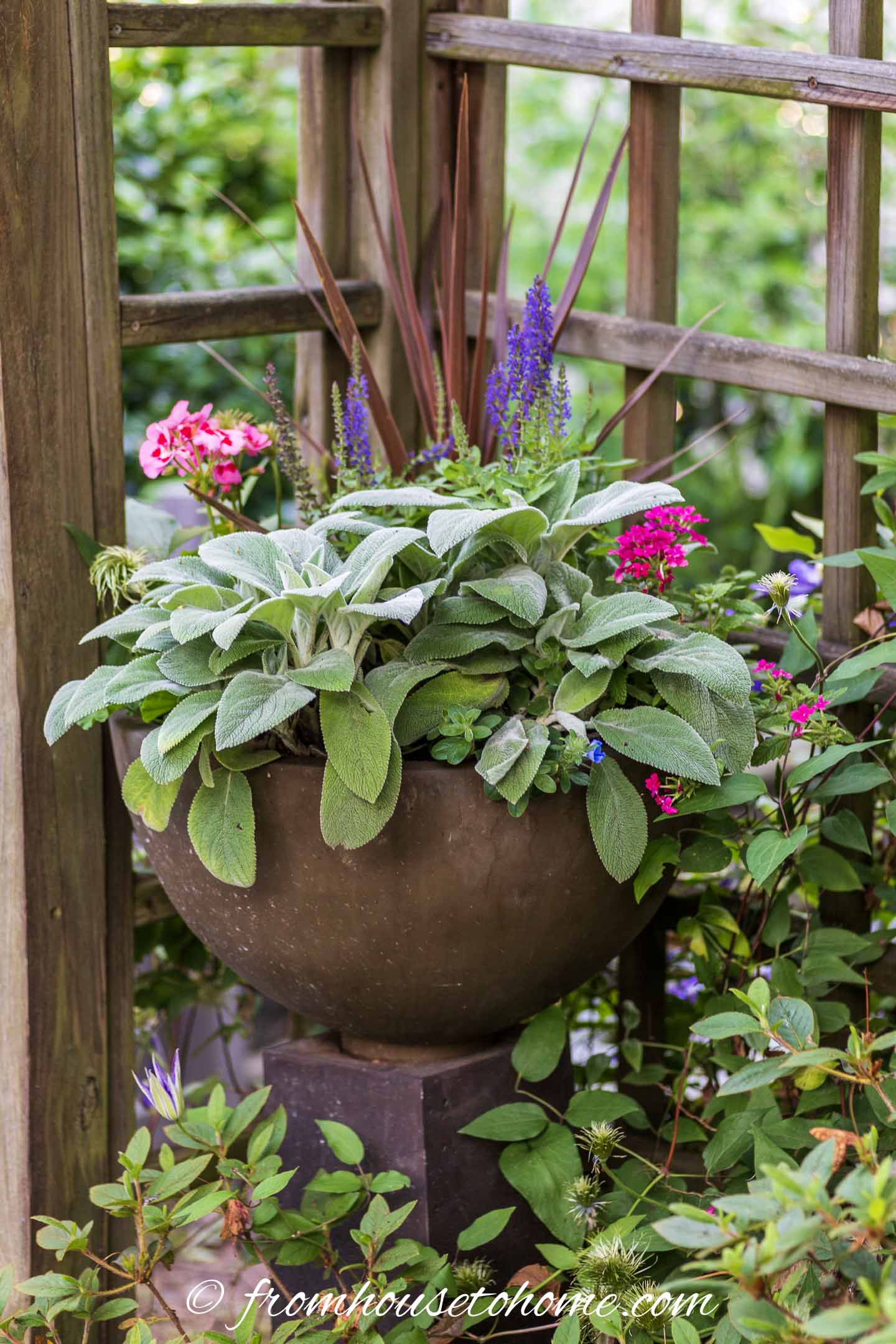 A container filled with blooming plants in front of a fence