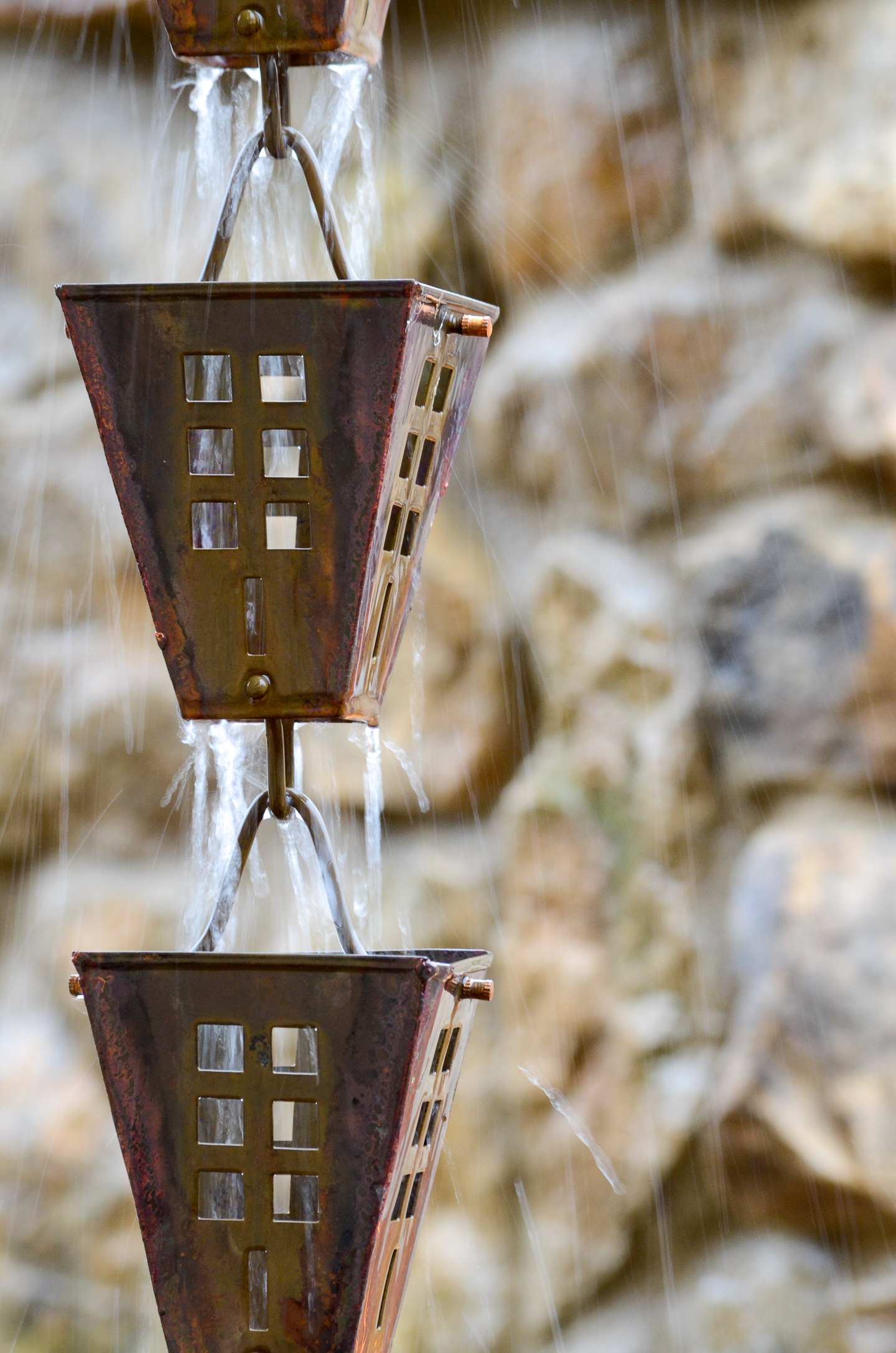 Copper rain chain with water running down it