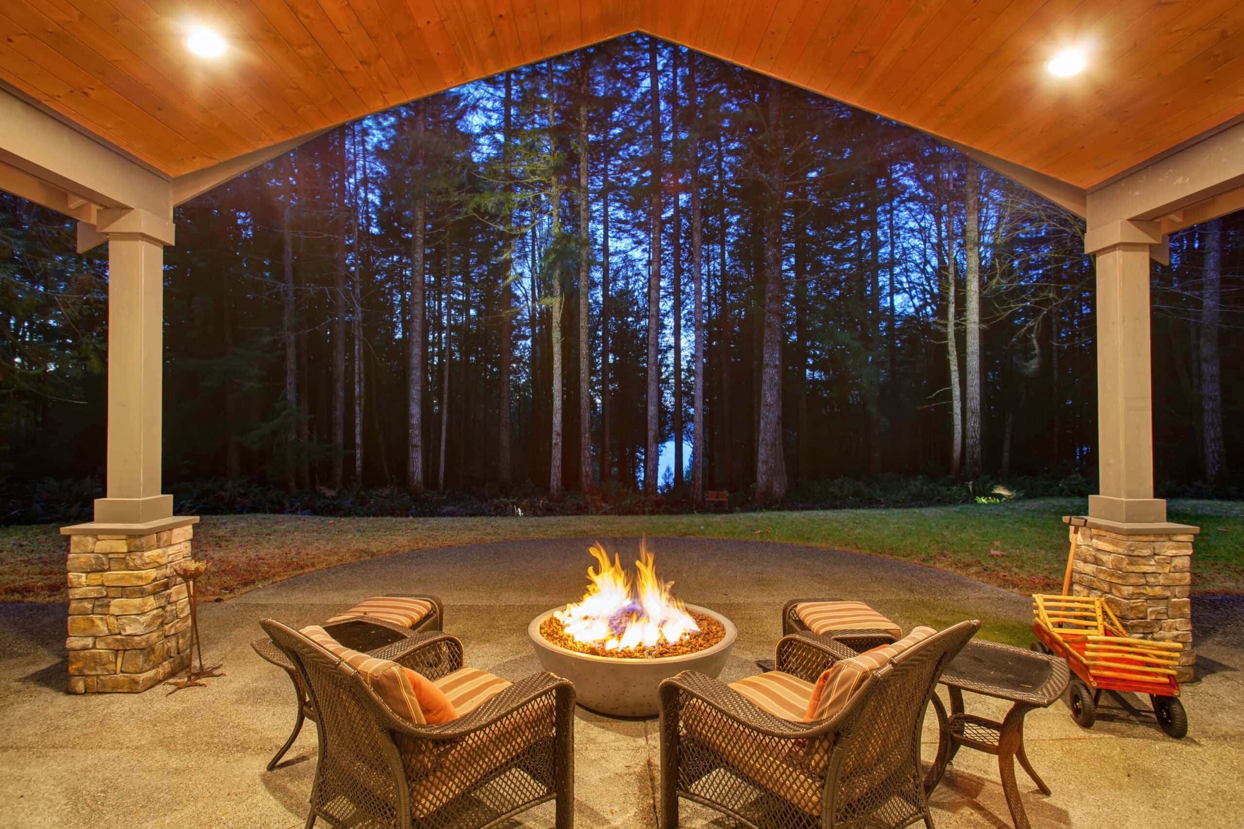 a cement bowl fire pit with two chairs under a pergola