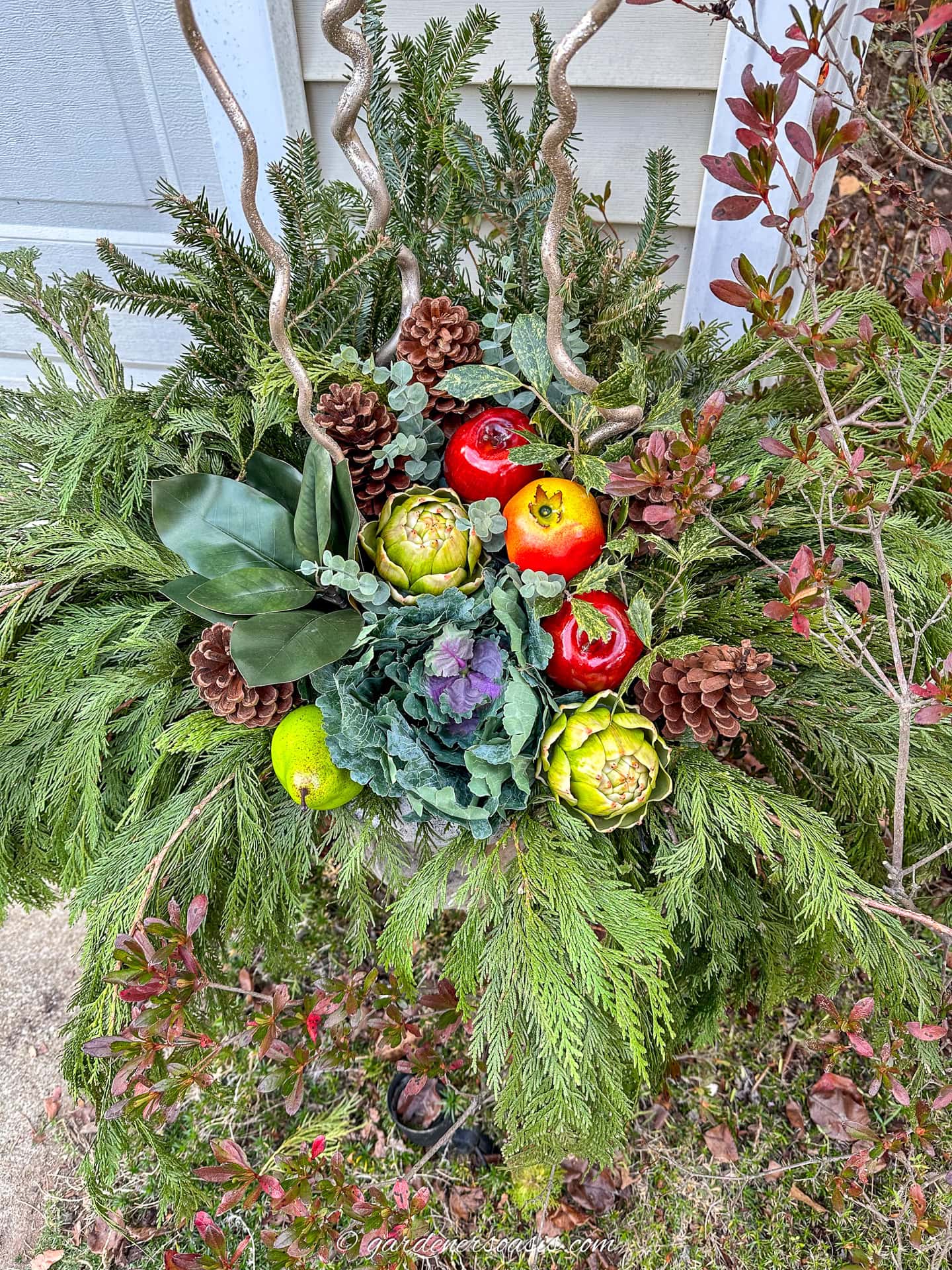 eucalyptus picks in a DIY urn winter planter with artificial fruit, pinecones, magnolia leaves, holly leaves, cedar, spruce and curly willow