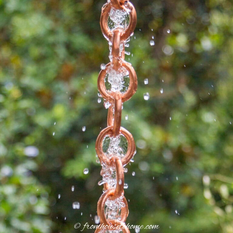 close up of a DIY copper link rain chain with water running down it