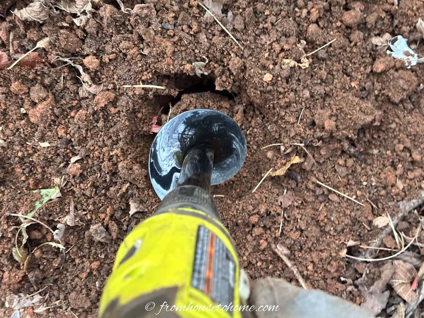A bulb auger digging a hole in the ground for planting bulbs