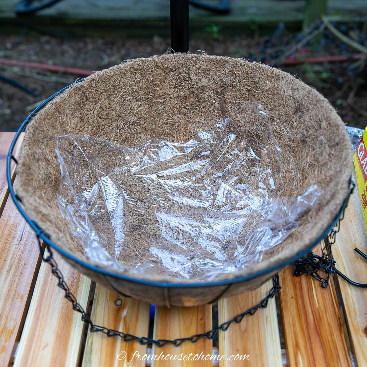 A hanging basket lined with plastic wrap