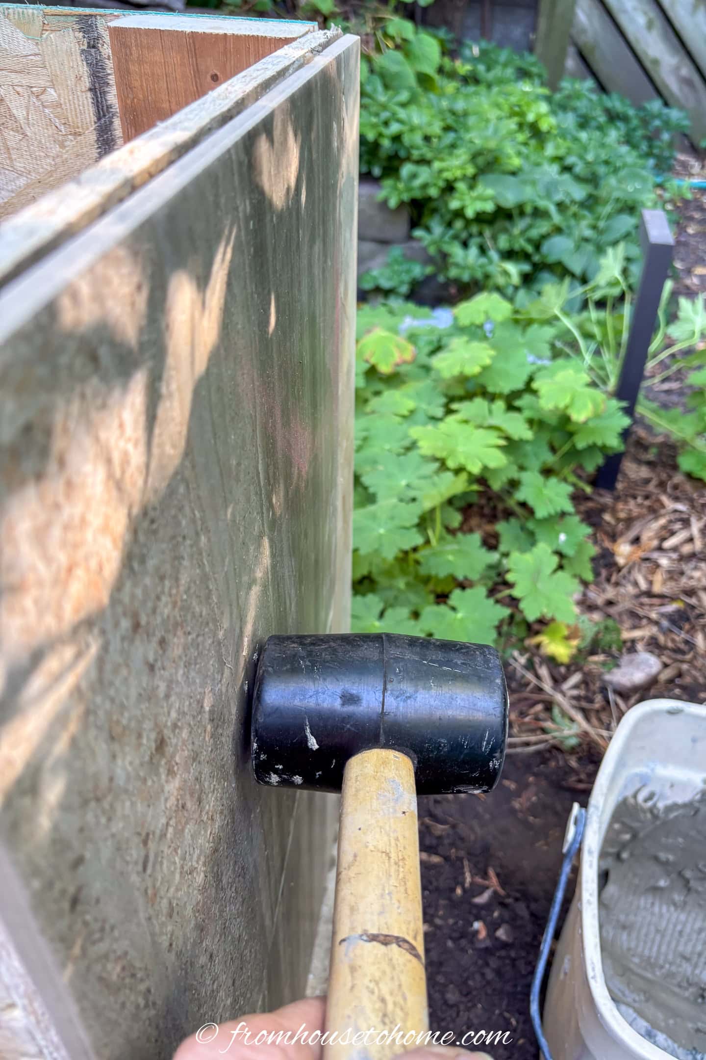 A tile being installed on the side of a plinth with a rubber mallet