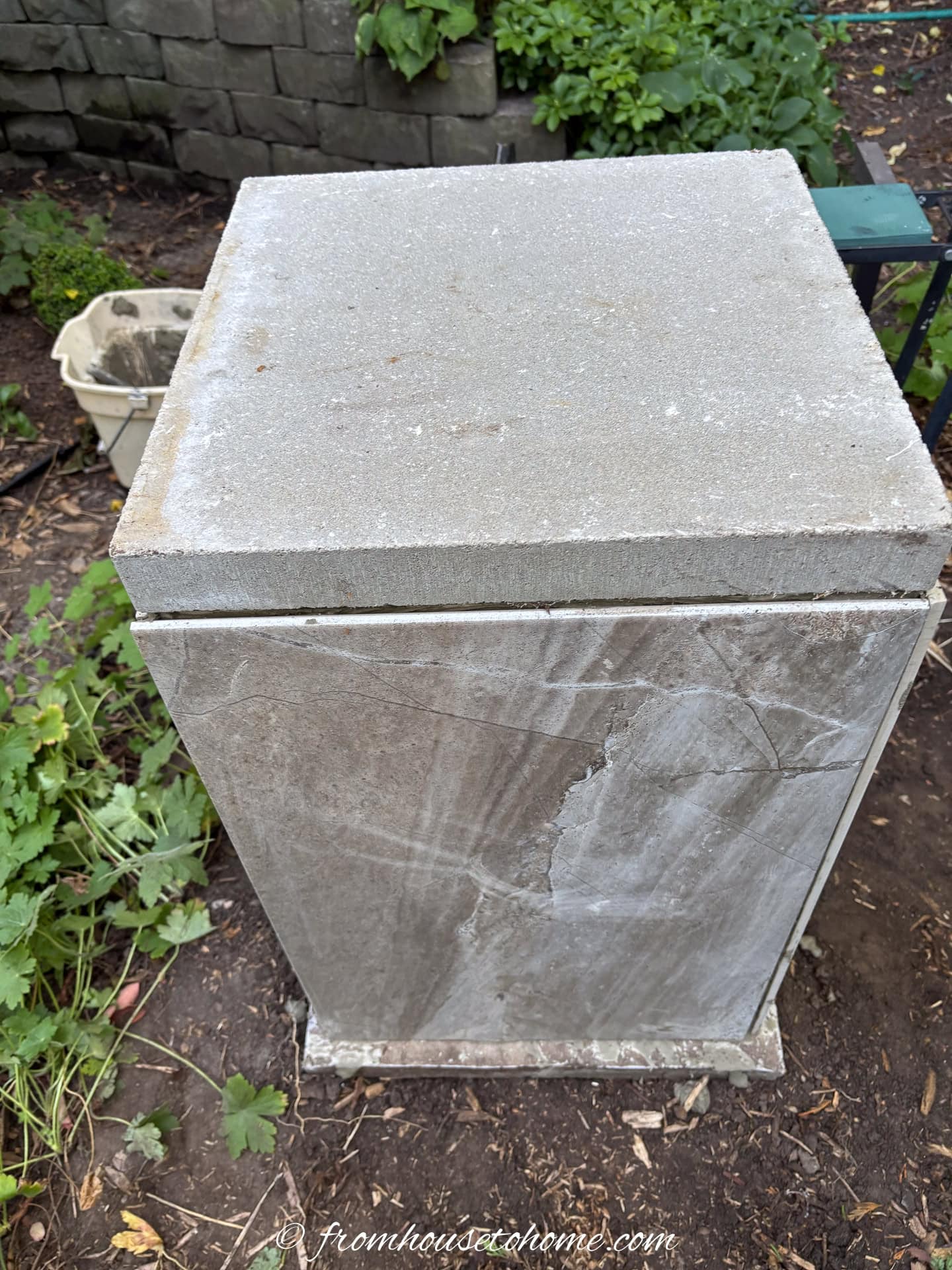 A DIY garden plinth with tile sides and a concrete block top