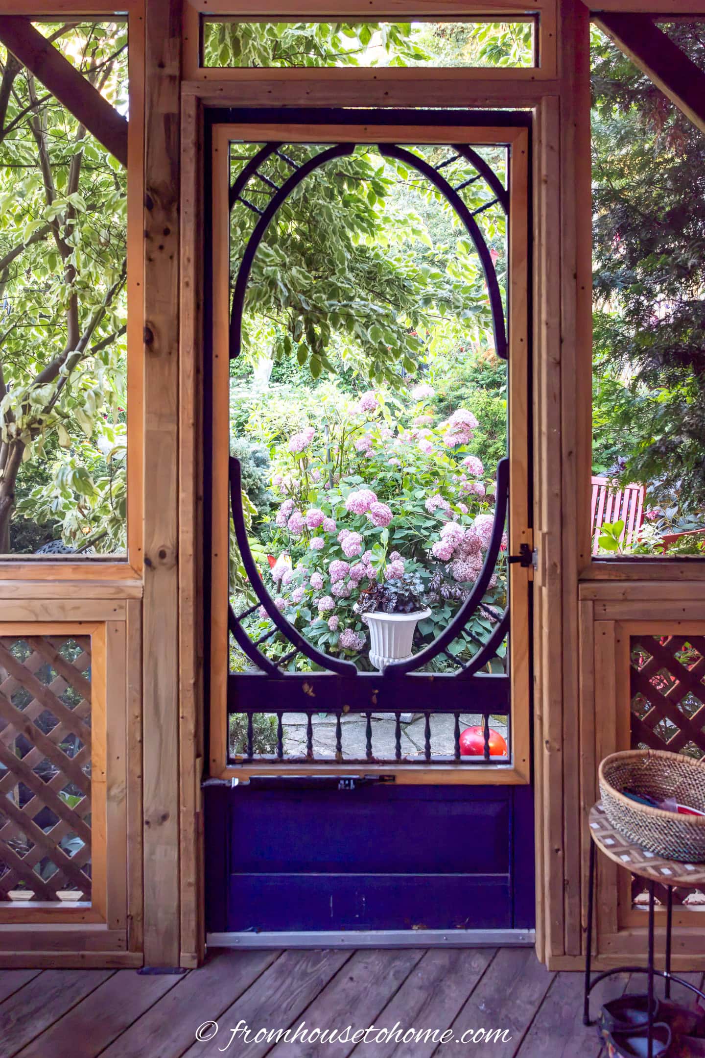 A decorative wood door frames a garden view from inside a gazebo