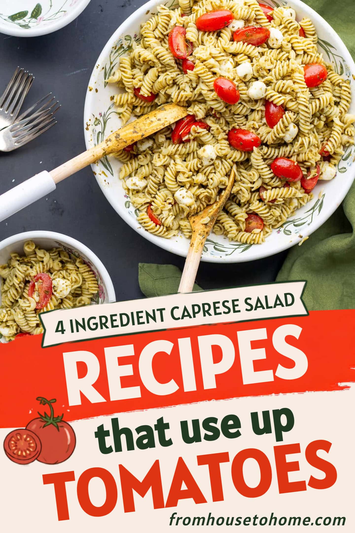 A bowl of rotini pasta salad with pesto, cherry tomatoes, and mozzarella balls, served with wooden utensils. A smaller portion is in a separate bowl beside it.