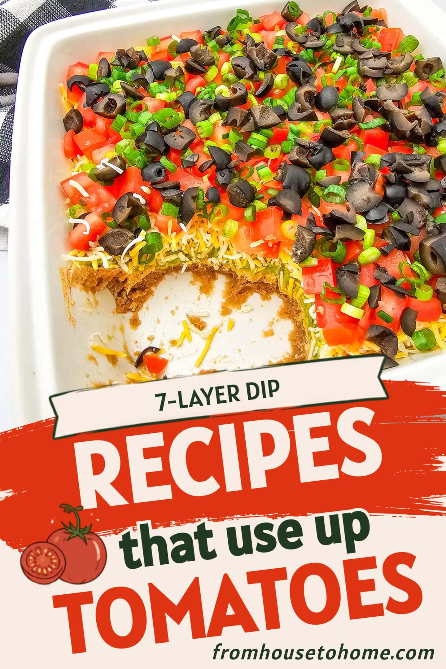 A casserole dish of seven-layer dip topped with chopped tomatoes, black olives, and green onions, with a portion scooped out from one corner.