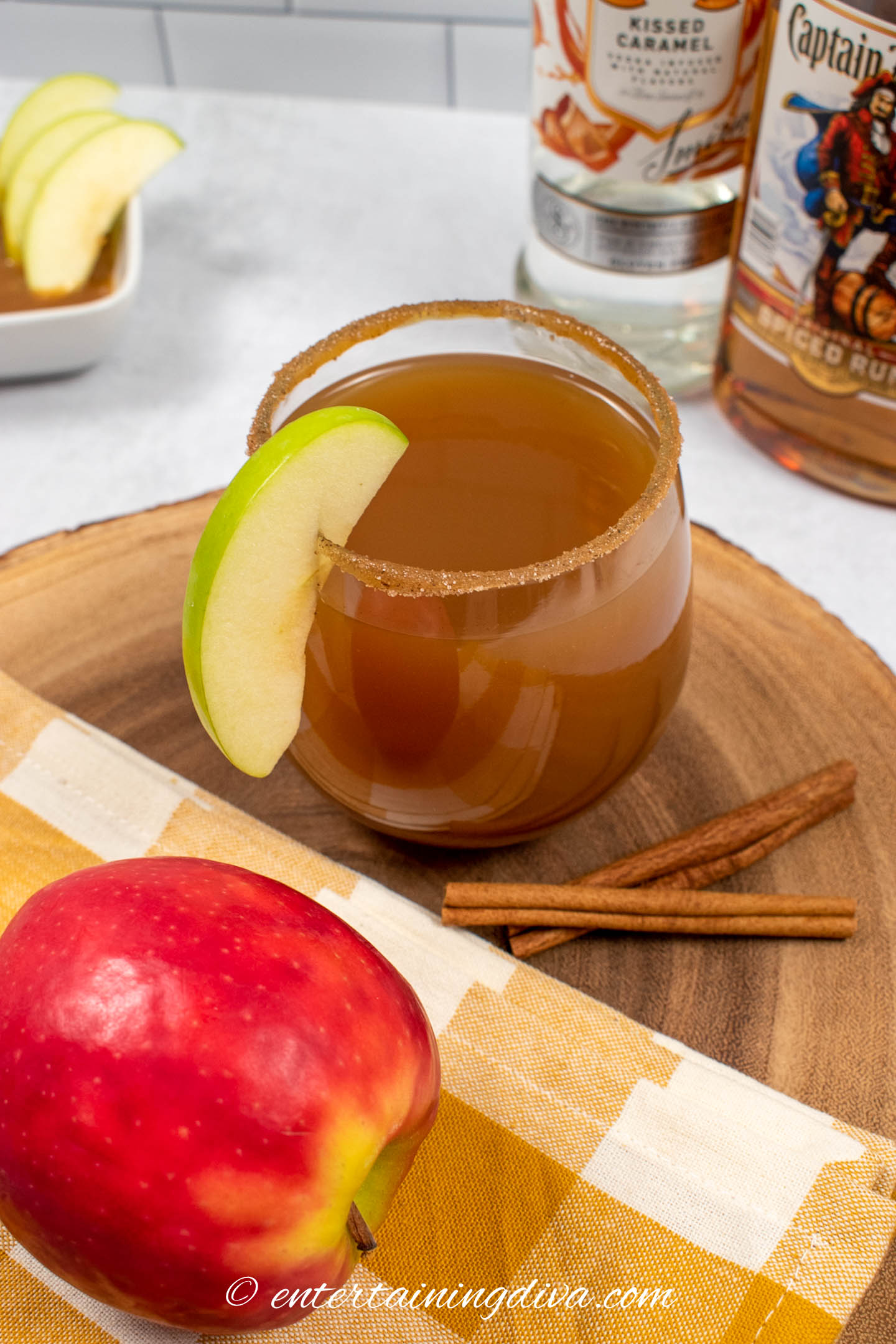 spiked caramel apple cider in a glass garnished with an apple slice