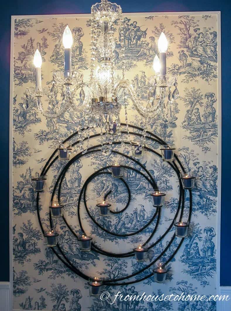 Chandelier and candles in front of a blue and white toile wall
