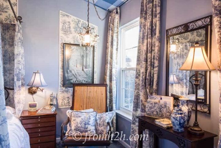 Blue and white bedroom with curtains that extend past the window