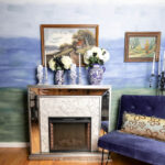 Fireplace and blue chair in front of a blue and green ombre wall painted with a watercolor technique