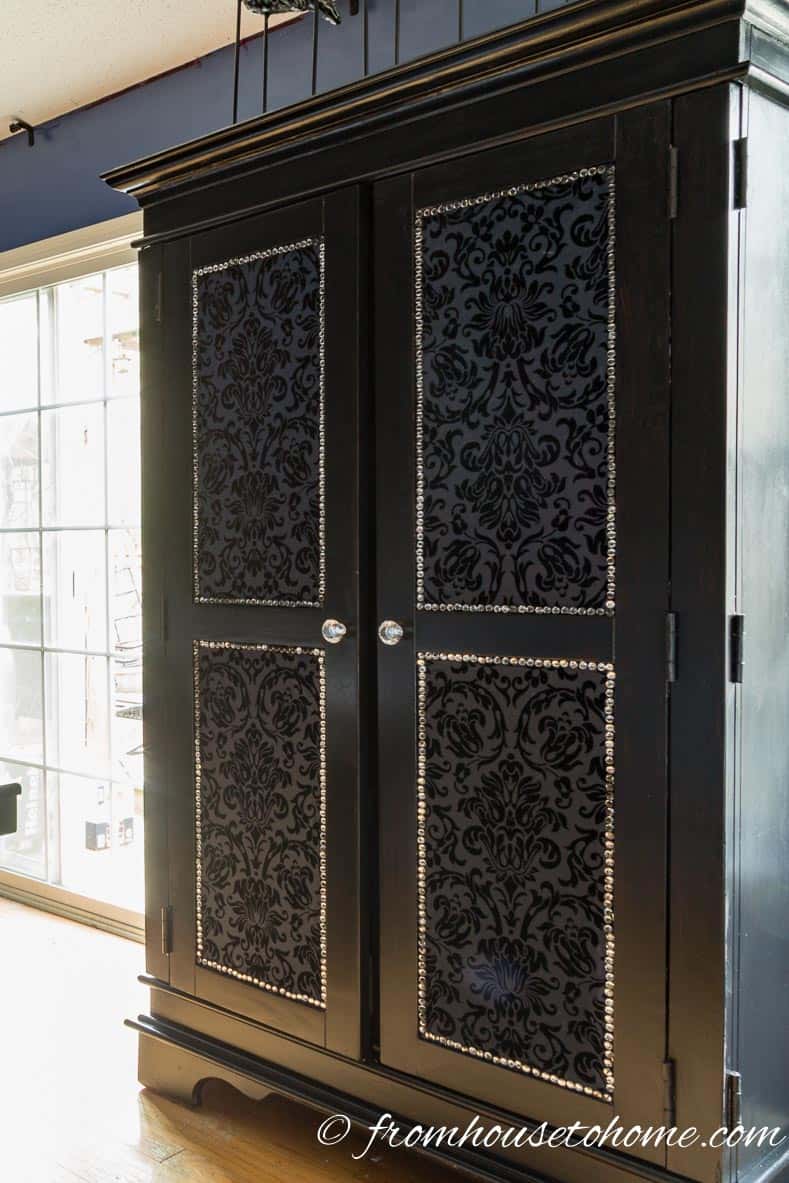 DIY upholstered armoire painted black with fabric door panels and crystal upholstery tacks