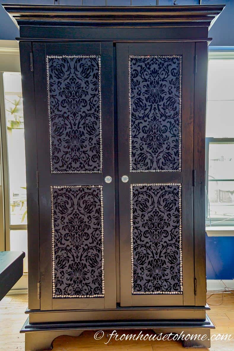 Front view of the black armoire with upholstered doors, crystal upholstery tacks and crystal door knobs