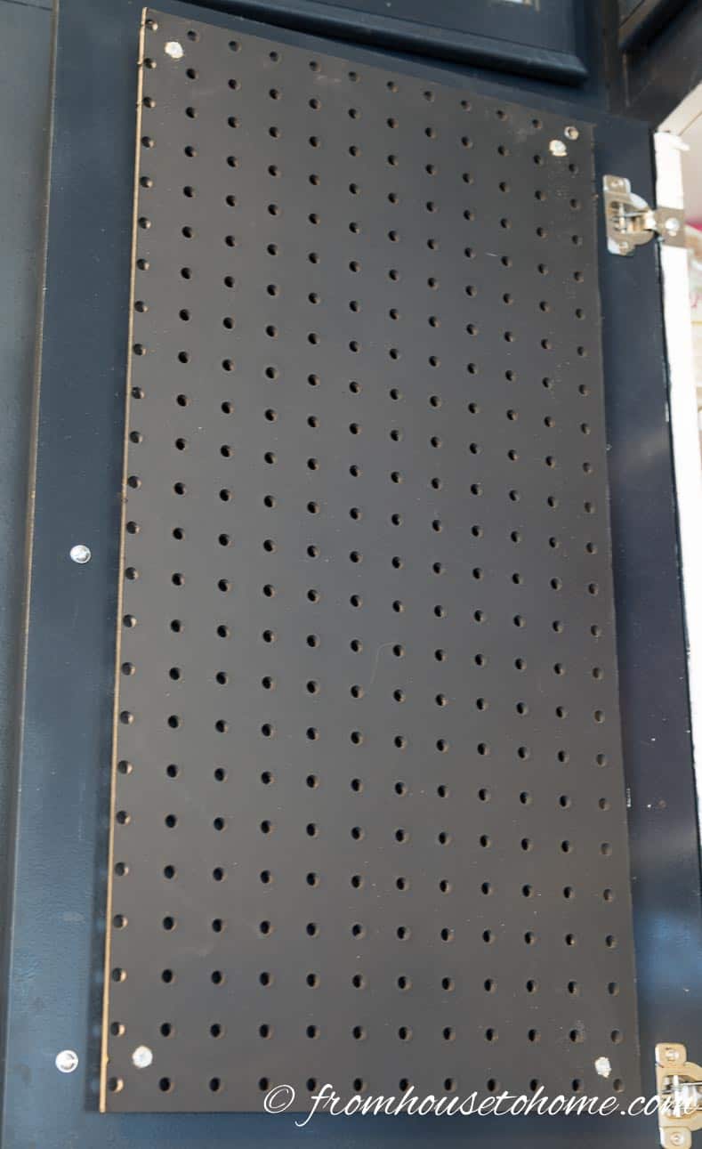 Install the pegboard on the inside of a kitchen cabinet door