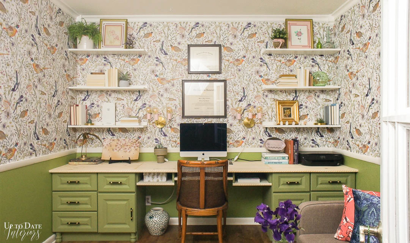 Green desk in a glam home office with birds on the wallpaper and coral pink accents