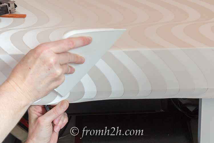 Hold the paper down while using the smoother to create a crease at the corner | How To Update A Countertop Without Spending A Lot Of Money