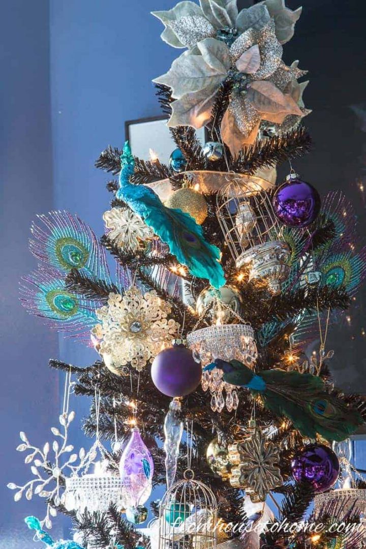 A black Christmas tree decorated with peacock ornaments