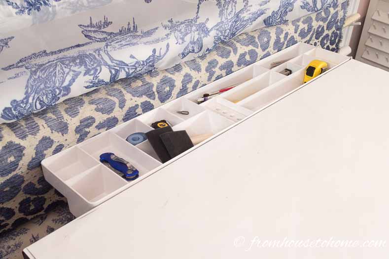 A drafting table tray used to organize craft room tools and supplies