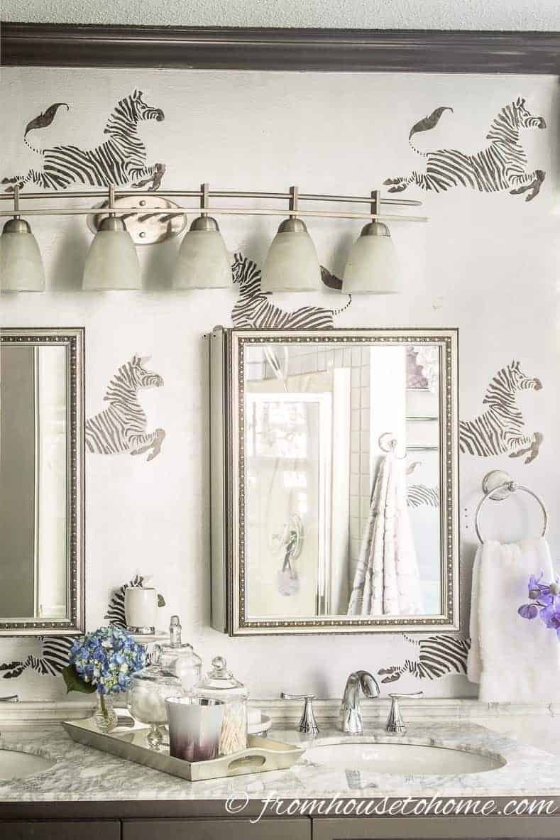 Silver bathroom wall with black and white stenciled zebras that looks similar to Scalamandre zebra wallpaper