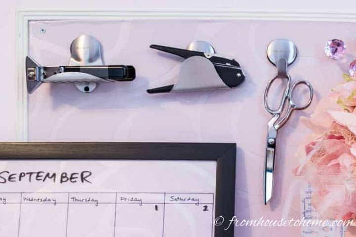 Magnetic sink holders on a DIY magnetic bulletin board holding up office tools