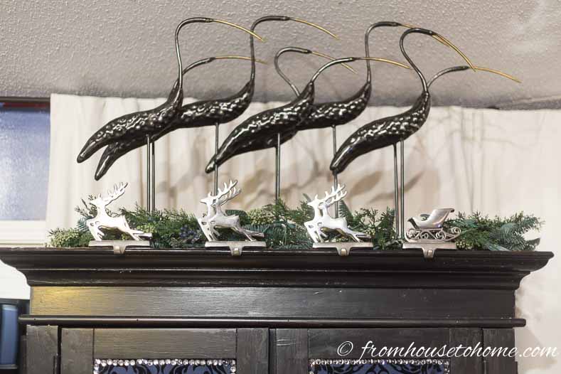 Reindeer stocking holders and evergreen branches on top of an armoire