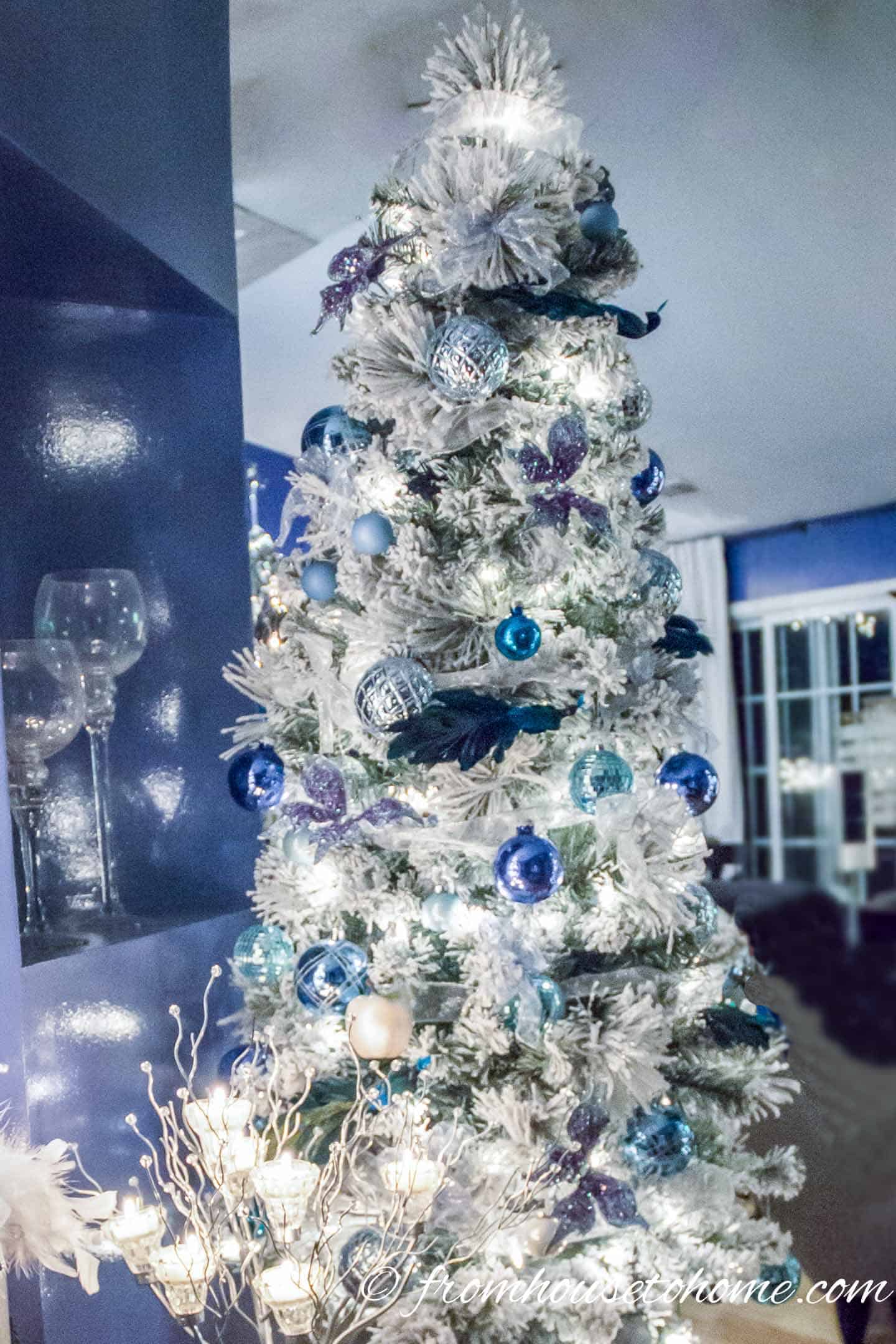 Peacock-colored Christmas ornaments on a flocked Christmas tree