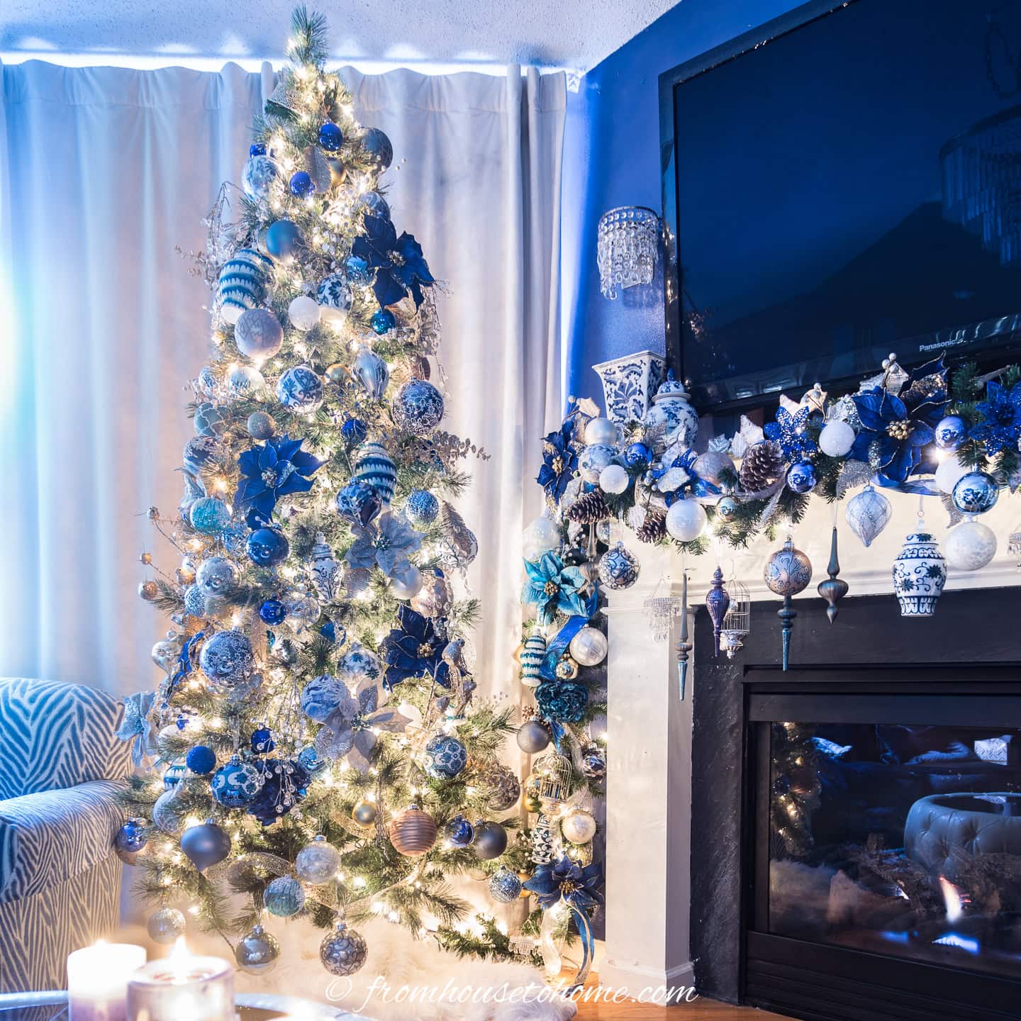 A blue and white Christmas tree beside a fireplace decorated with a blue and white Christmas garland