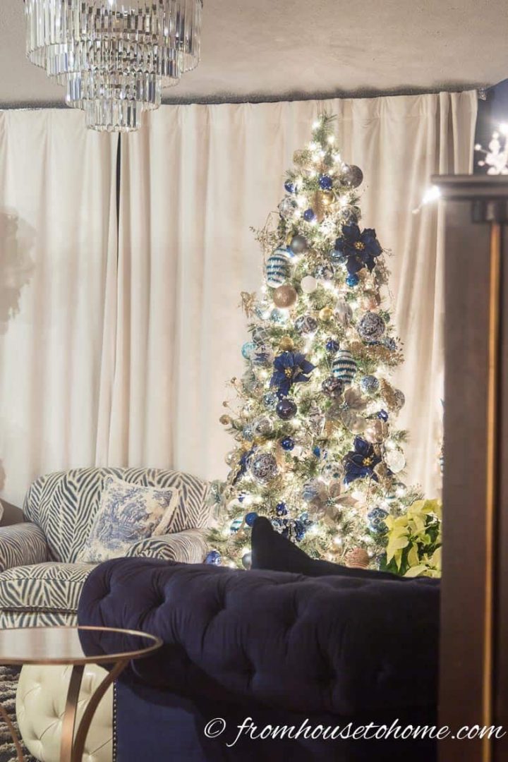 Blue, white and gold Christmas tree in front of white velvet drapes
