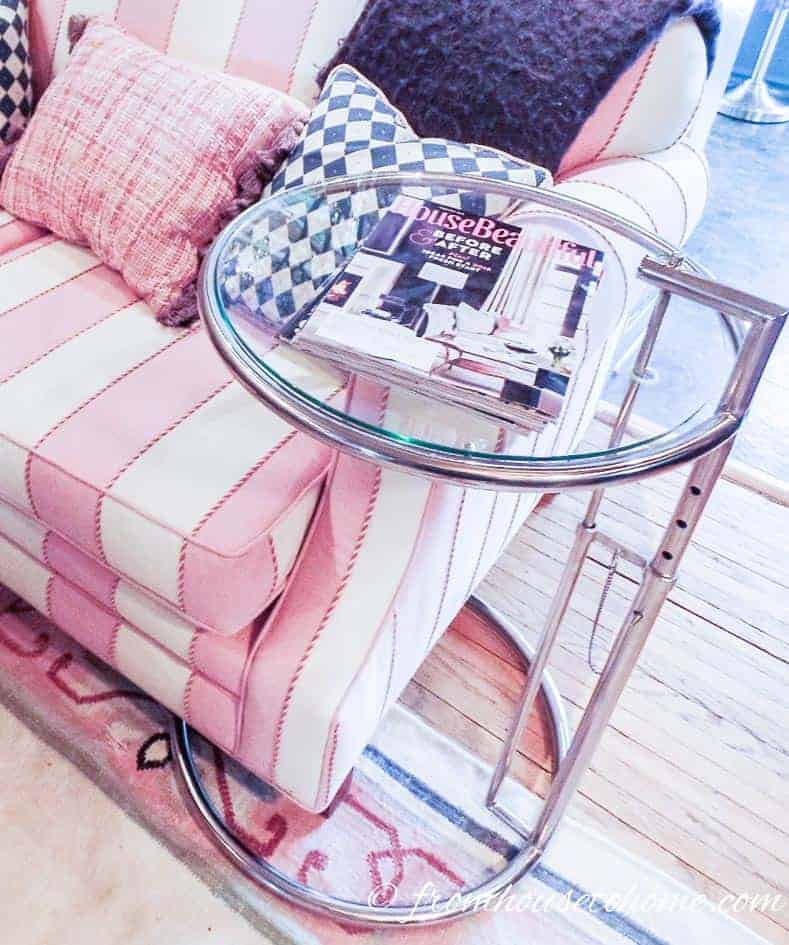 Eileen Gray glass table over the arm of a pink and white sofa