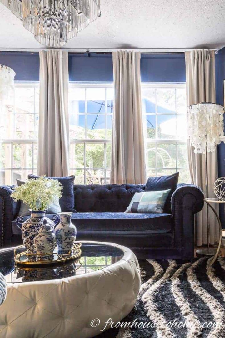 White velvet curtains behind a blue velvet sofa in the living room